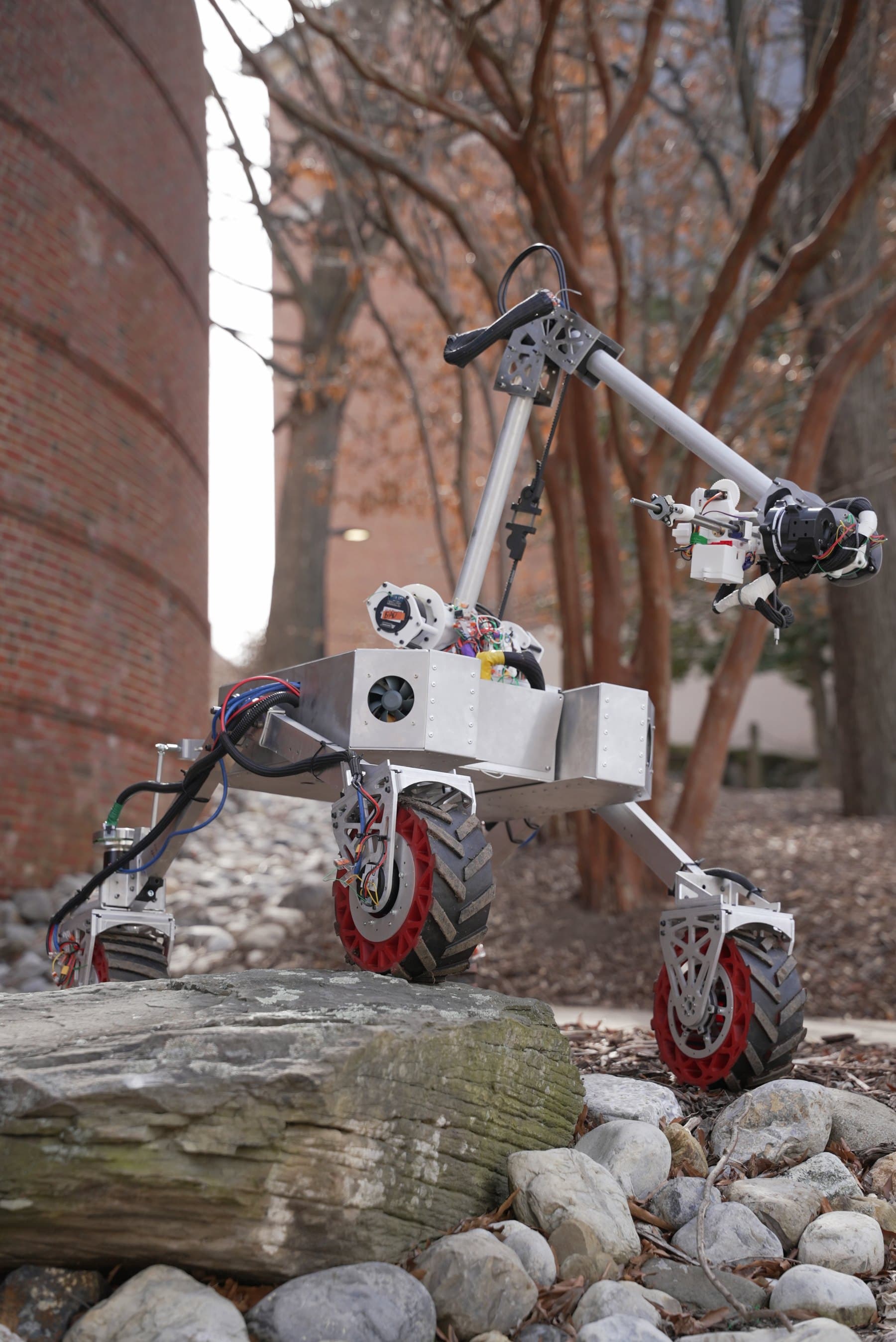 Six-wheeled robotics rover with a manipulator arm climbing over rock.