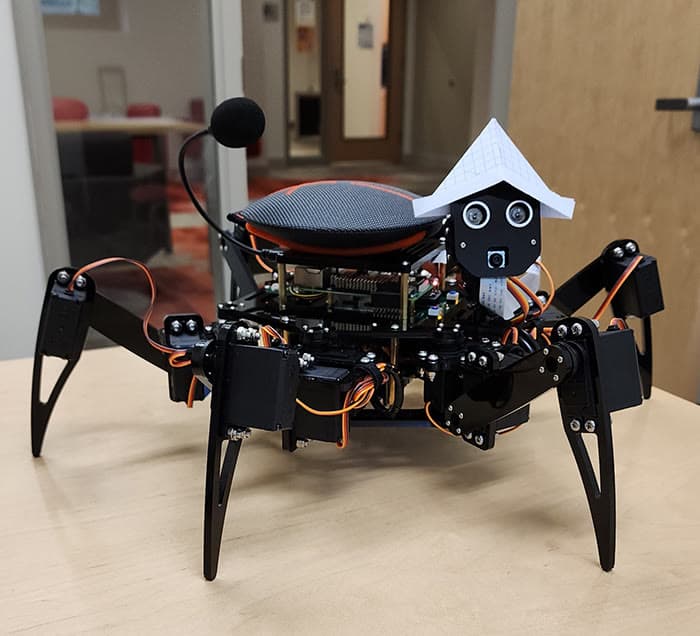 Six-legged spider robot with servo-driven joints on a workshop bench.